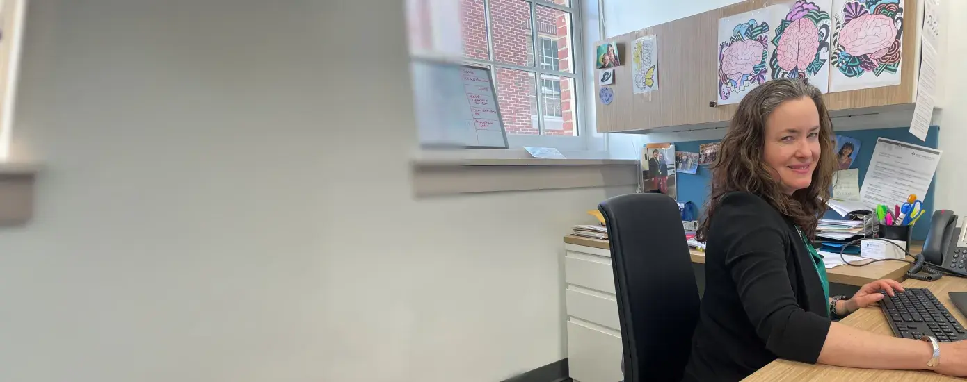 A woman sits at a desk with a keyboard in front of her
