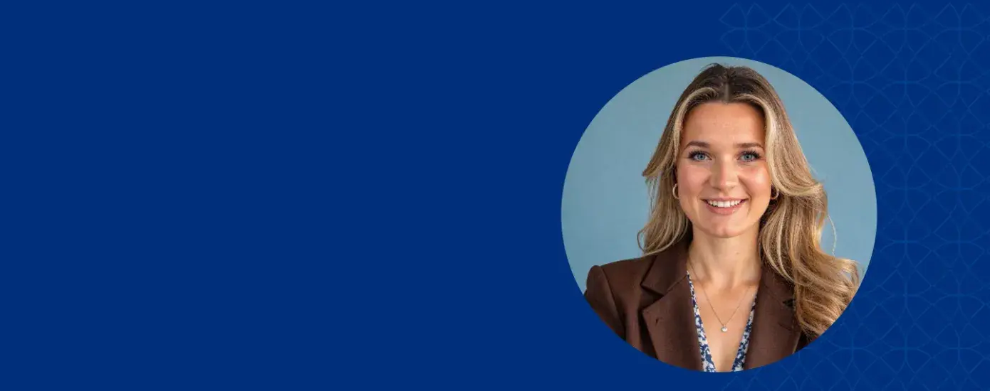 Woman with blonde hair smiling and wearing a brown jacket