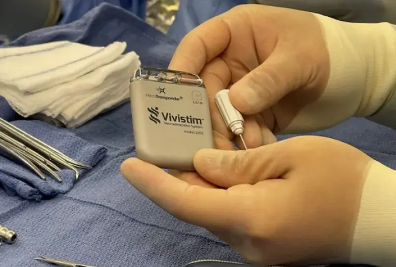 gloved hands hold a grey rectangular device over sterile surgical towel