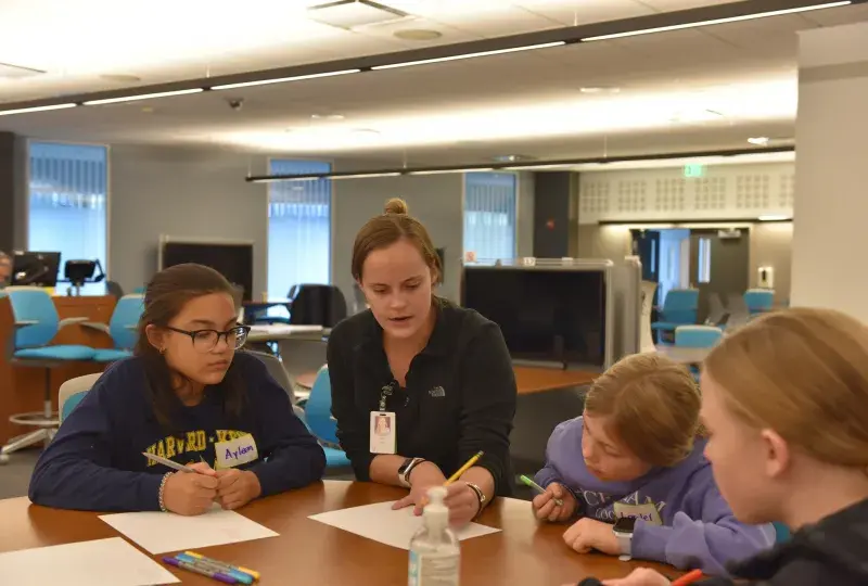 Fifth-grader, Ayleen (left) watches nursing student Lauren O'Neil (center). They're joined by two other Harvard-Kent students