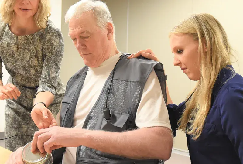 Photo of Dr. Teresa Kimberley (left) works with a patient (center) and a grad assistant at the Brain Recovery Lab on the MGH Institute campus.