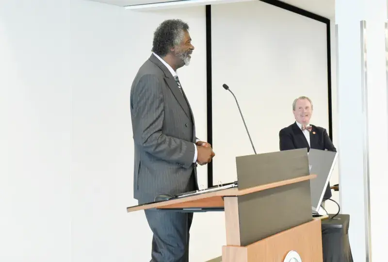 Black man in grey suit speaks