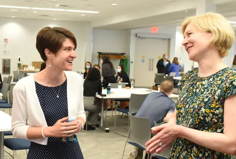 Two women share a laugh in a room.