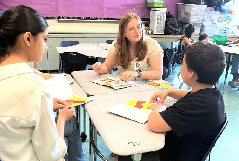 Two women at a table talking with a young boy