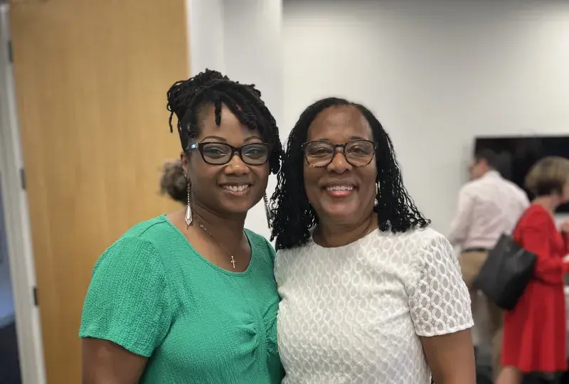 Two women stand and smile