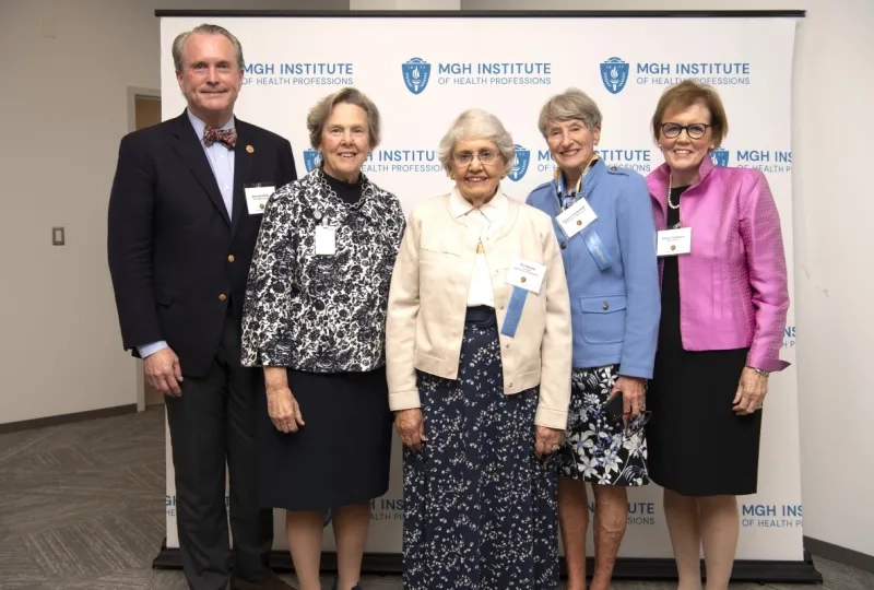 Five people smiling and standing in front of a banner