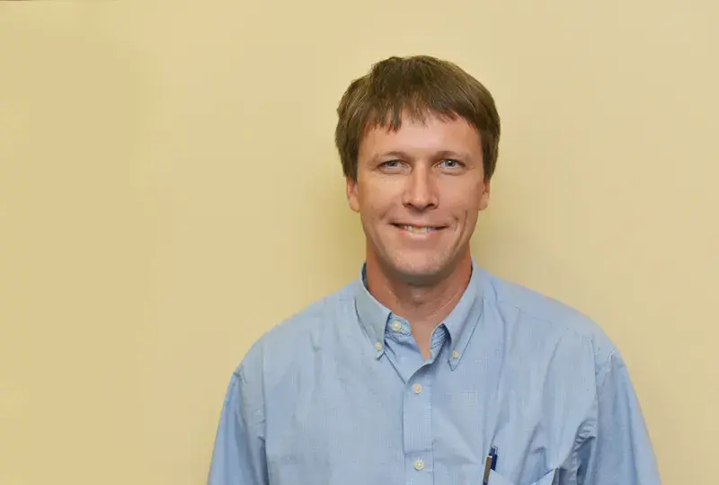 jason wears a blue collared shirt and a smile
