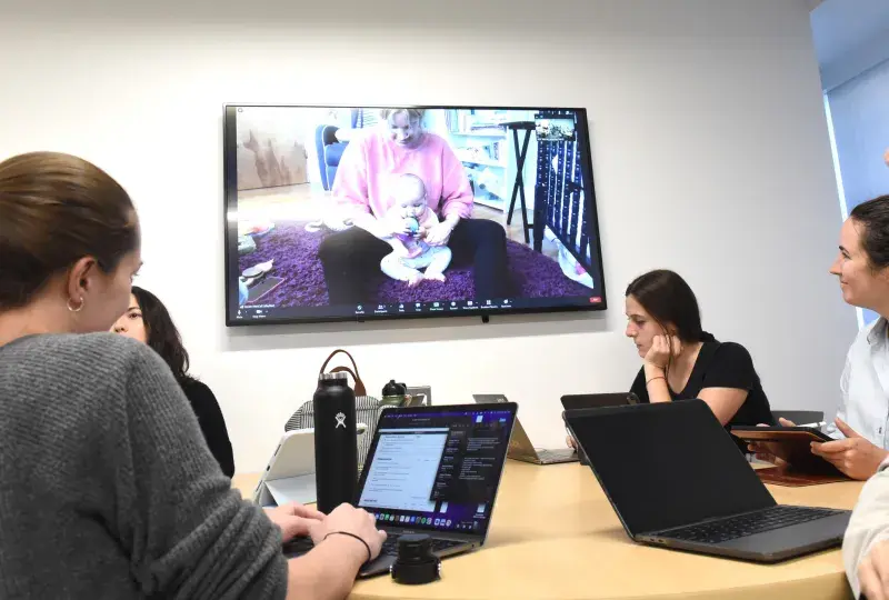 People sitting around a table watching a wall monitor