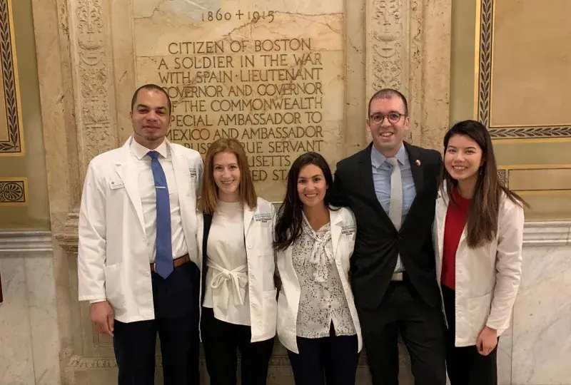 two men stand with three woman at state house