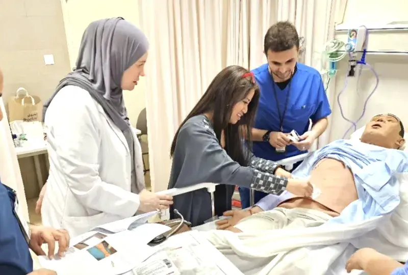 People working with a manikin in a hospital bed