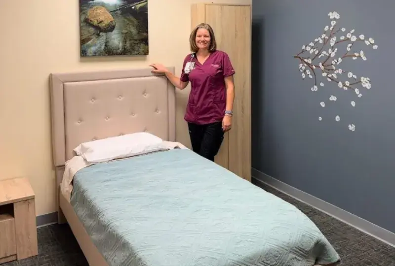 woman stands next to bed