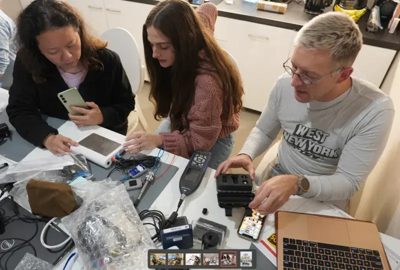 two women and man work with audiology equipment at table