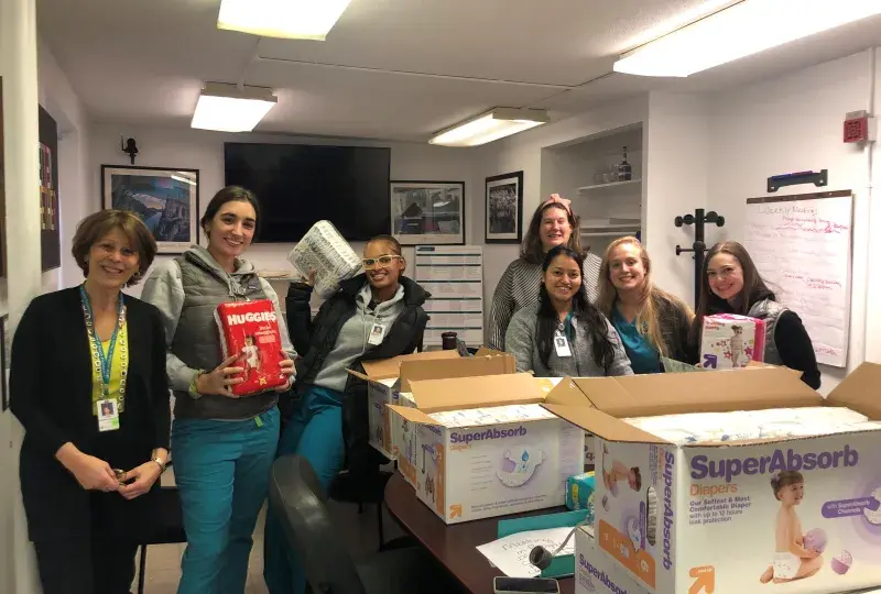 seven women stand with diapers in room