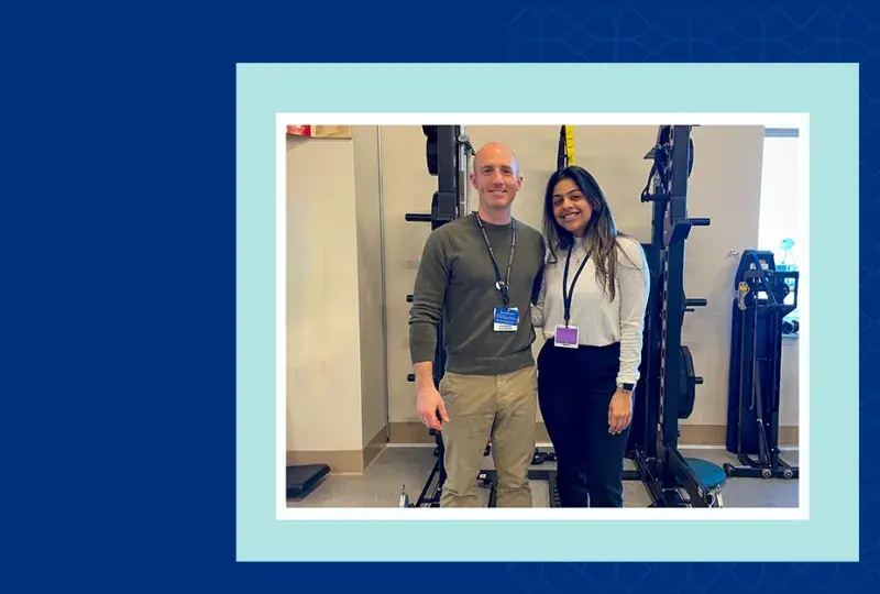 two people pose together in front of a room of exercise equipment