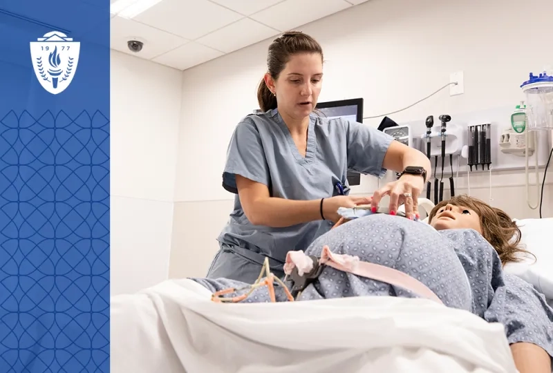 woman in scrubs adjusts a strap on a pregnant manikin in a hospital bed