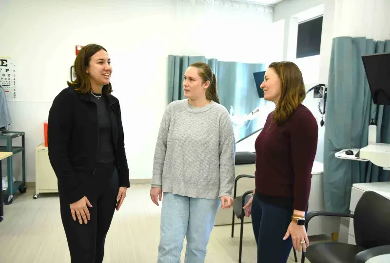 Three people talking in nursing lab