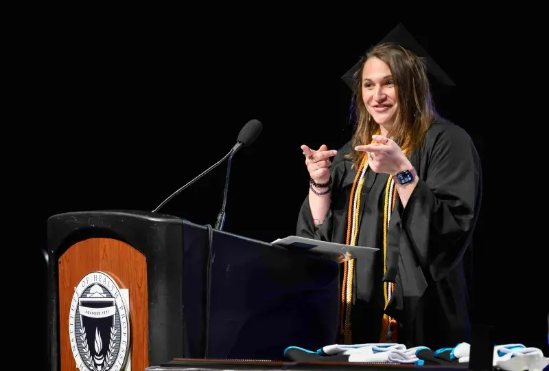 Woman in cap and gown talking at podium