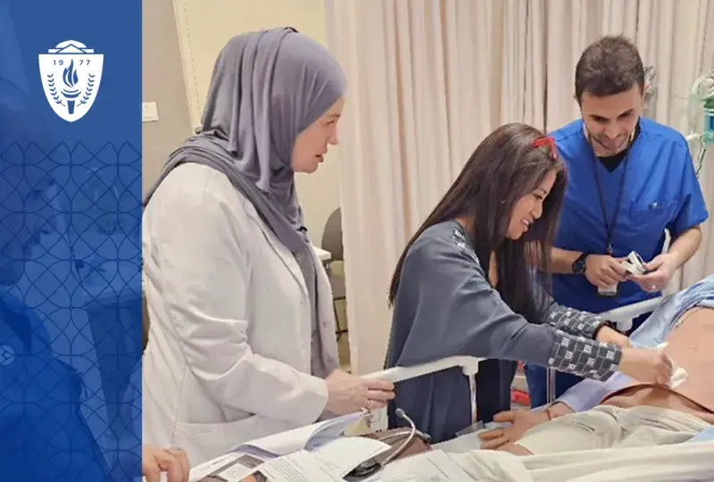 a woman shows two students something on a manikin's stomach at a hospital bedside