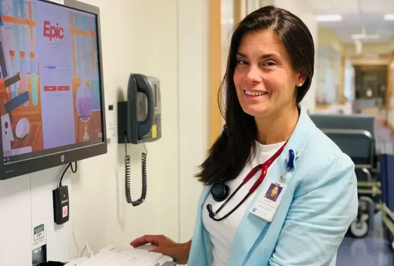 woman standing at a computer in a hospital hallway