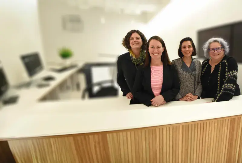 four women stand behind a desk