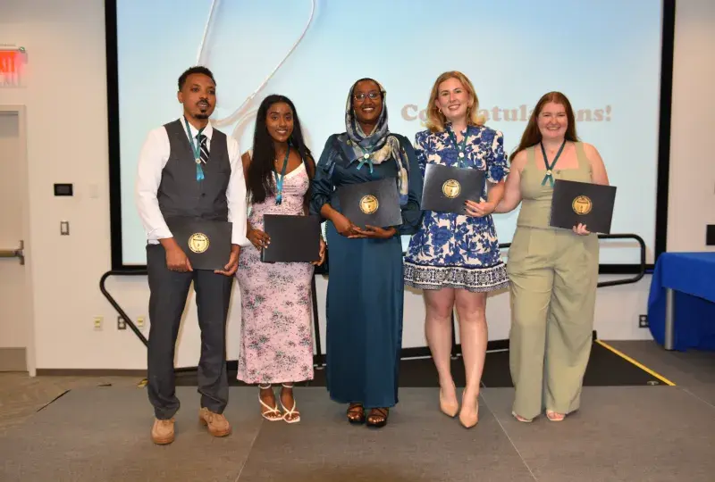 Five people pose with awards