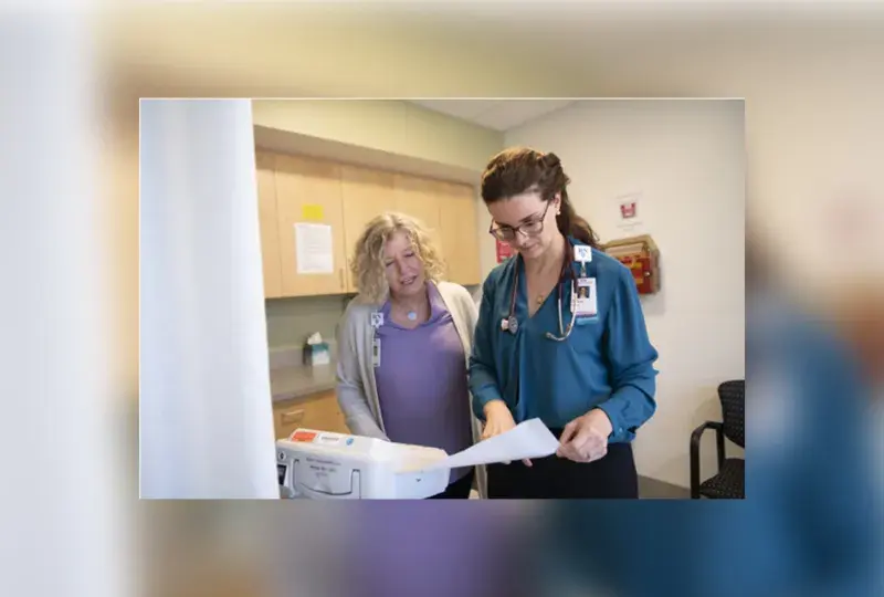 a woman with a stethoscope on looks at a paper while another woman looks over her shoulder