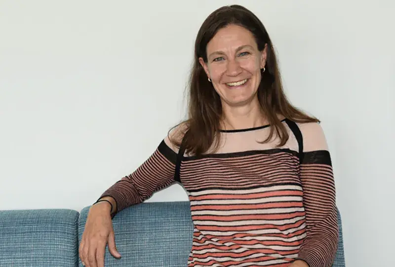 A woman sits on a couch facing the camera