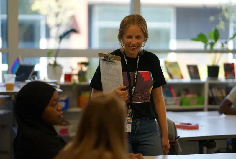 A professional in the MGH IHP Literacy and Language Certificate Program poses confidently in a modern academic setting. The program prepares educators for leadership roles in literacy education, emphasizing teaching reading and writing skills, and literacy leadership training. 