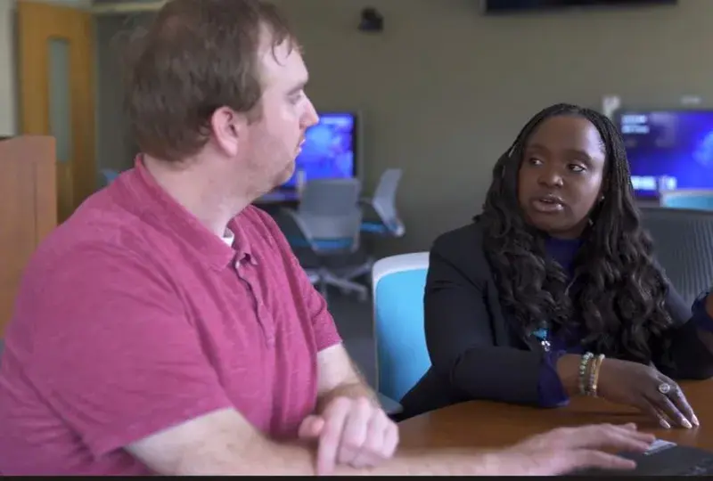 A man and woman sit next to each other at a table talking