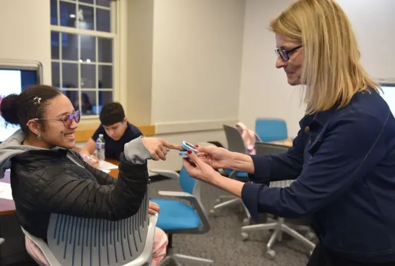 A woman places a device on the finger of a woman who is sitting down