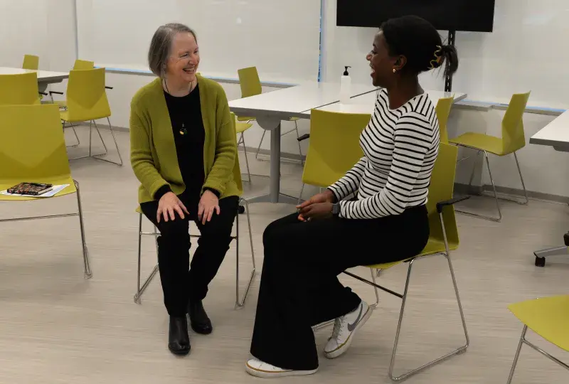 two women sitting in chairs and smiling 