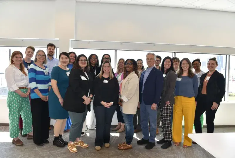 A group of people pose in front of windows