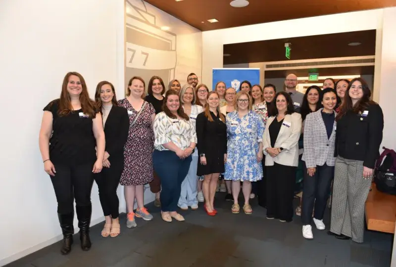 A group of people pose for a photo in front of a wall. 