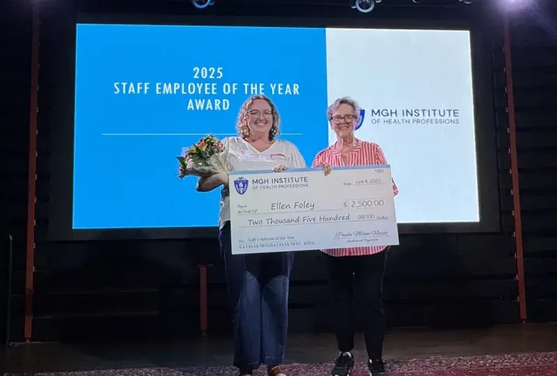 A photo of two women on a stage holding a check.