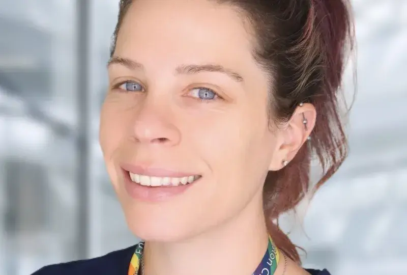 Brenna has a high ponytail and a rainbow lanyard around her neck