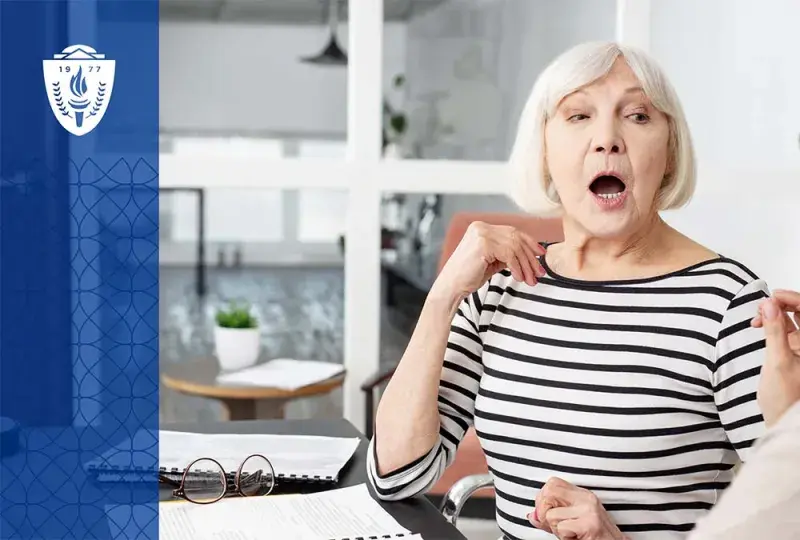 Older woman with white hair sitting at a table working with a speech language pathologist