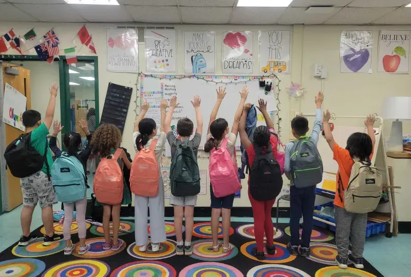 KIds holding hands up with backpack
