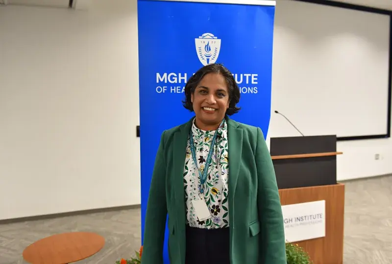 A woman stands in front of a blue banner