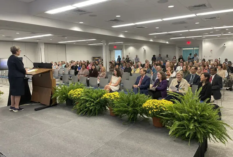 woman at a podium speaking to a mixed crowd
