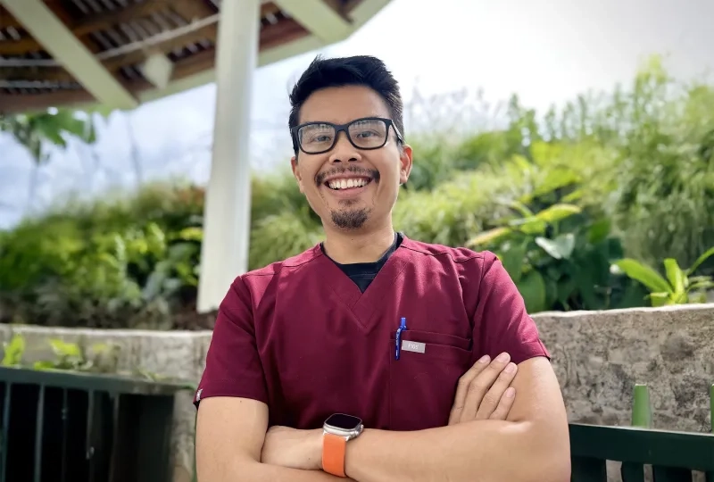 Man standing with big grin in a tropical location with arms folded