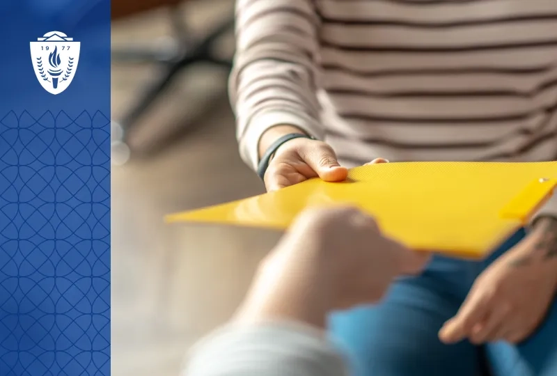 Close up of a person handing a yellow folder to another person.