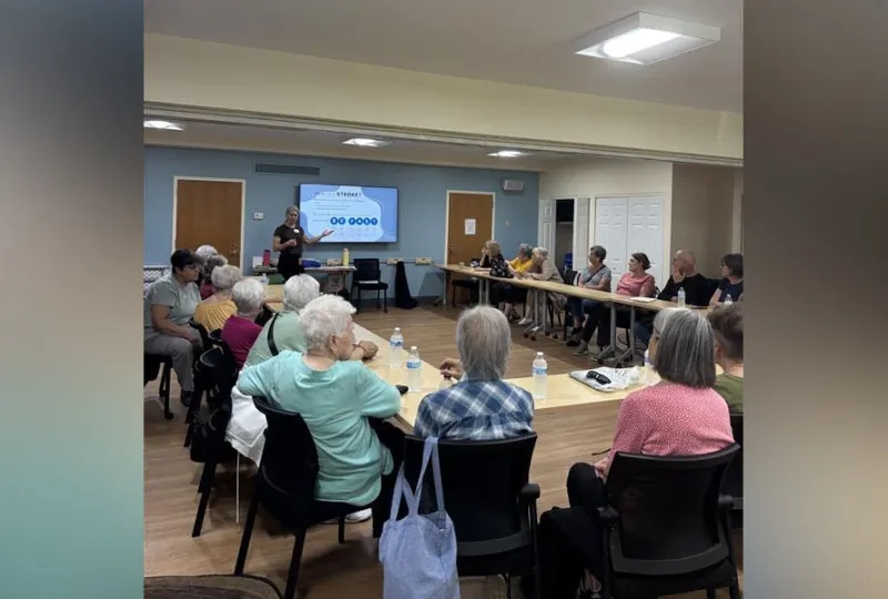 woman in front of smart board in room full of people