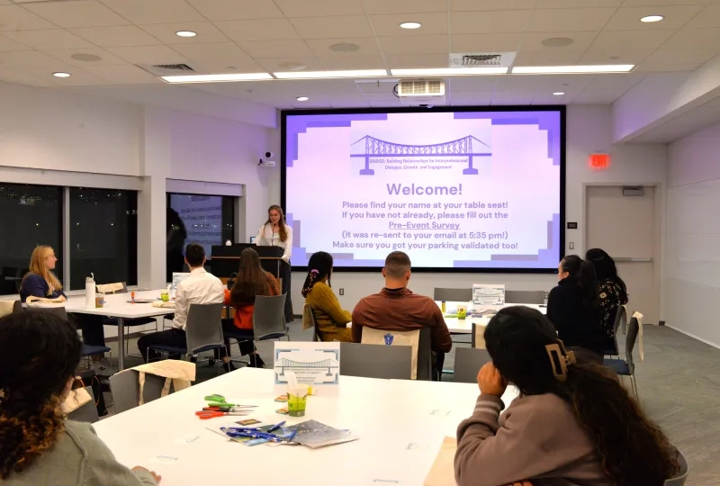 Wide shot of people sitting at tables in large room 