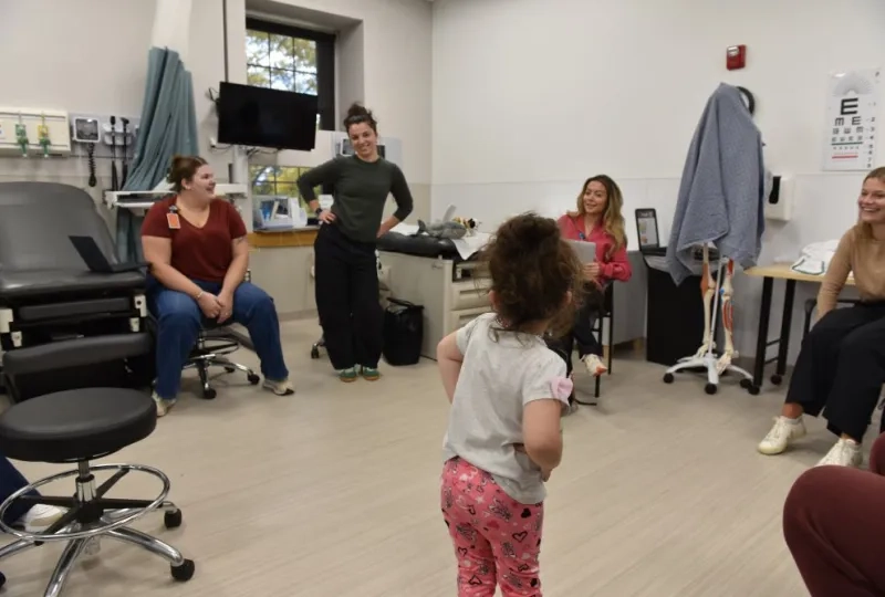 Small child with hands on hips in front of 4 women 