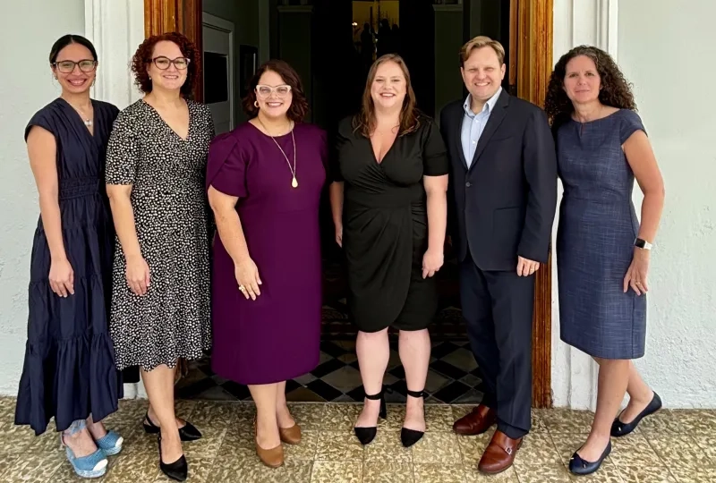 Six people post in front of a doorway
