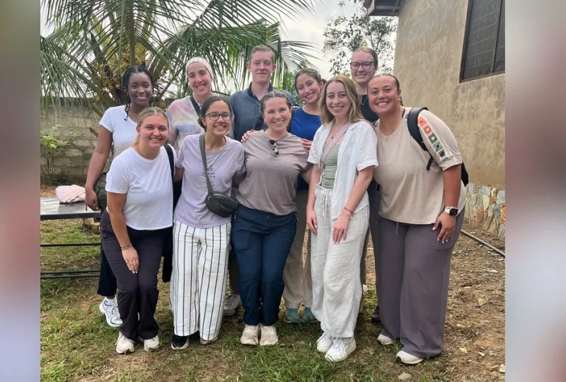 Ten people stand in two rows to pose for photo