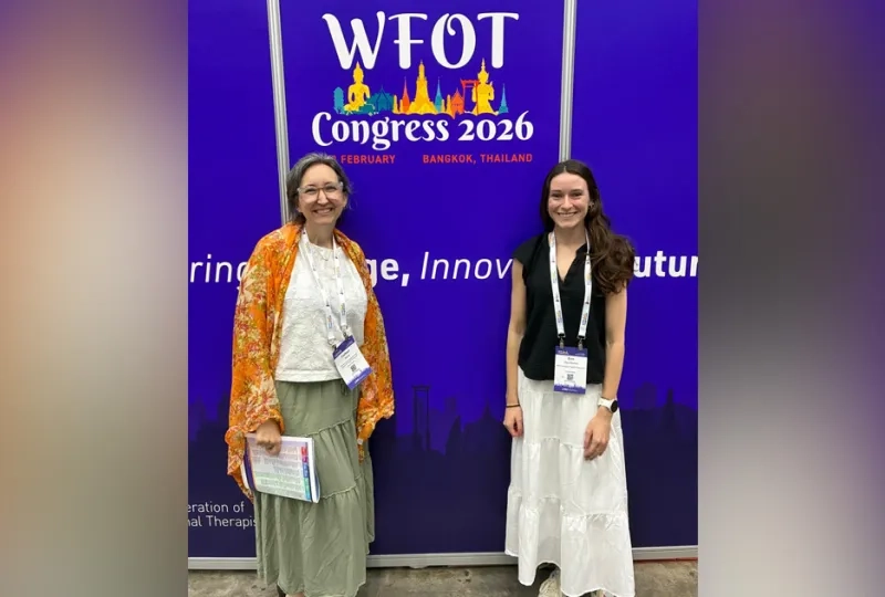 Two women standing in front of a backdrop with WFOT Congress 2026 Printed on it