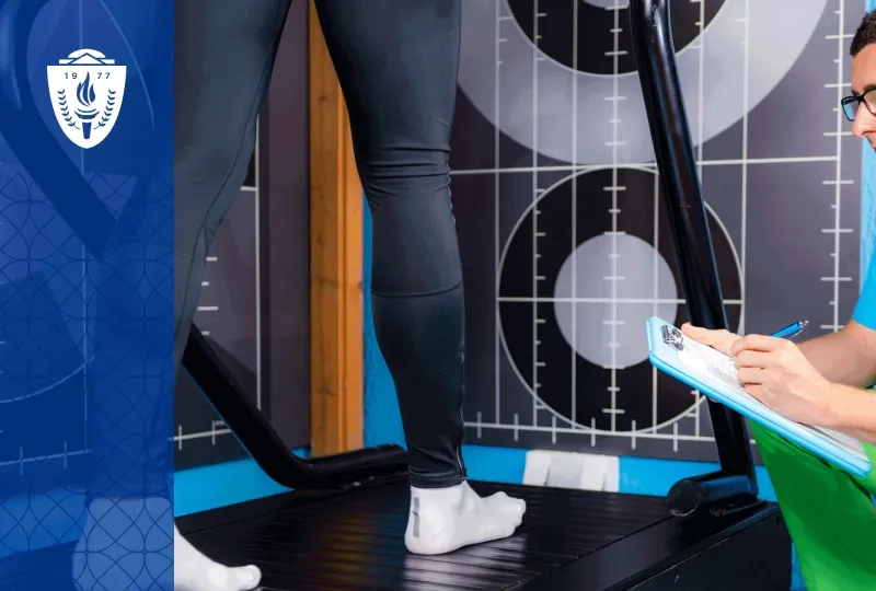 Man crouching with a clipboard and studying a person walking on a treadmill