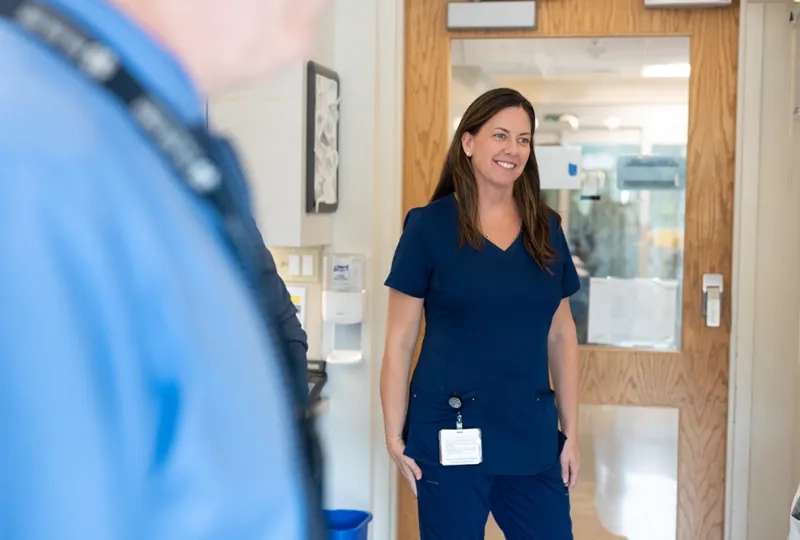 A woman wearing medical scrubs stands in a hospital room