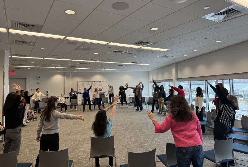 Group of people in a circle with their arms raised.